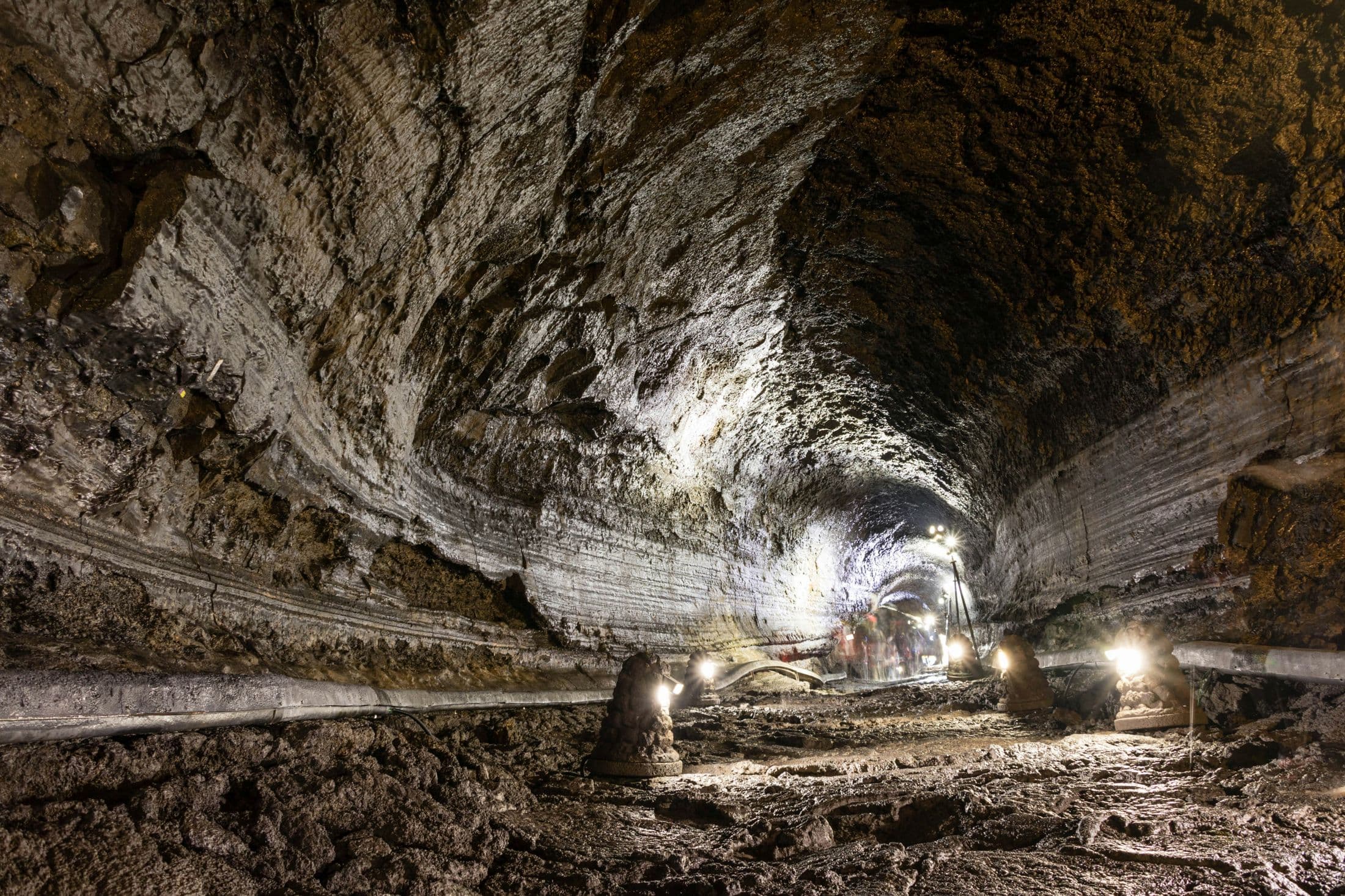 The lit face of an underground mine tunnel, crews working deep below surface.